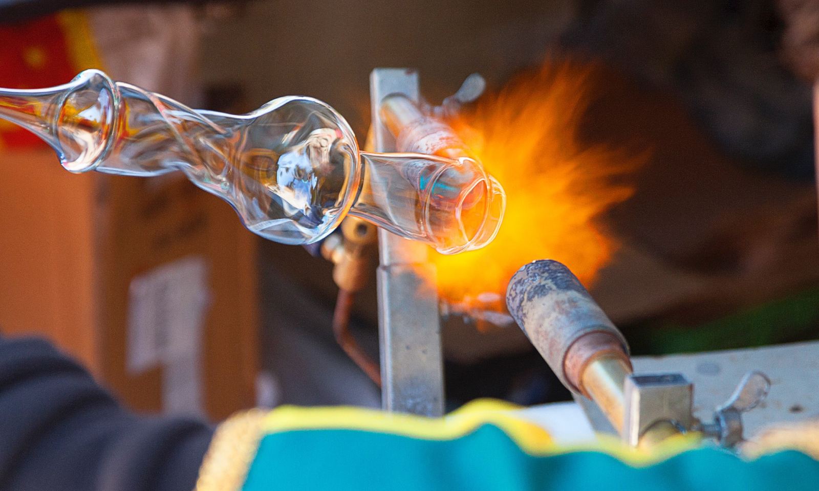 A glass-blower shaping a vessel in a torch flame